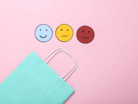 customer satisfaction survey concept. Shopping bag with happy, neutral and sad face paper icon on pink background. top viewの写真素材