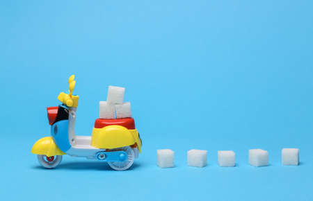 Toy scooter with sugar cubes on blue backgroundの写真素材