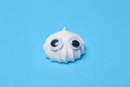 funny portrait of cute Sweet meringue with eyes on blue backgroundの写真素材