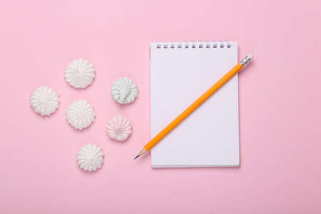 Master chief. Culinary blog. Sweet meringue with notebook on pink background. top view
