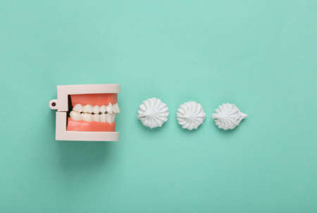 Human jaw model with Sweet meringue on blue background. concept pop. top view. flat lay
