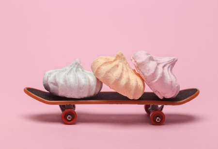 Sweet meringue on skateboard, pink backgroundの写真素材
