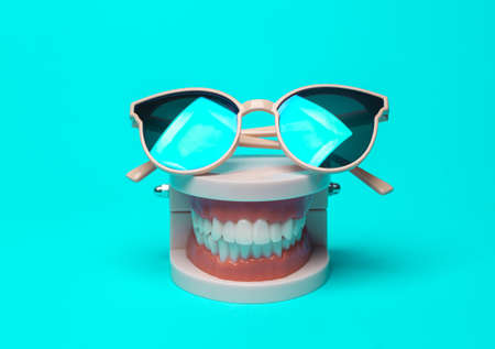 Model of a human jaw with sunglasses on a bright turquoise background. Minmal still life. concept popの写真素材