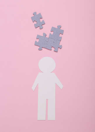 Business, mental health, dementia. Paper cut man with puzzle pieces on a pink backgroundの写真素材
