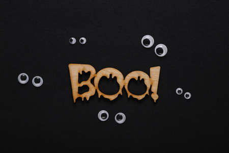 Minimal halloween layout. The word boo! with frightened goggles on black background. top viewの写真素材