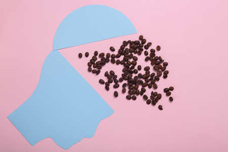 Coffee lover, energy boost for the whole day. Paper head silhouette with coffee beans on pink backgroundの写真素材