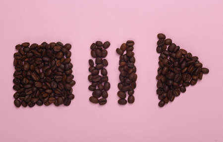 Coffee beans in the shape of start, stop, pause icons of media player on pink background. top view