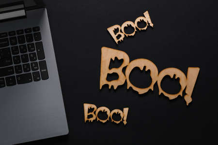 Happy halloween concept. Words boo! with a laptop on a black background. top view
