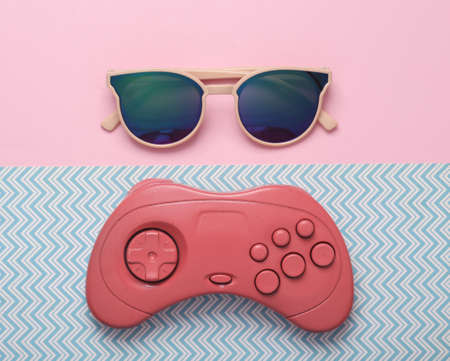 Gamepad with sunglasses on blue pink background. top view. flat lay