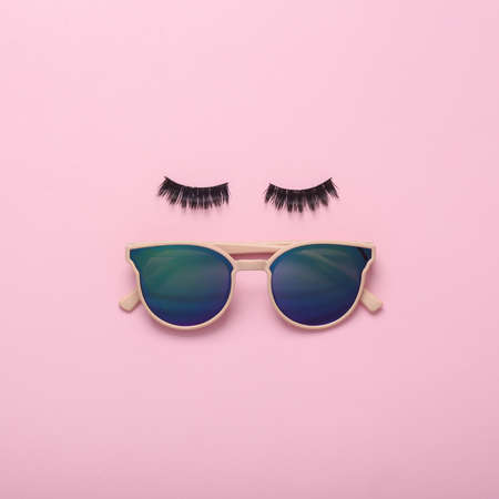 Eyelashes with sunglasses on a pink background. Minimal creative layout, beauty conceptの写真素材