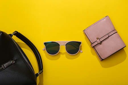 Stylish fashionable women's accessories on a bright yellow background with a shadow. Wallet, bag and...