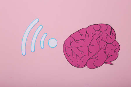 Paper brain with wifi waves icon on pink background