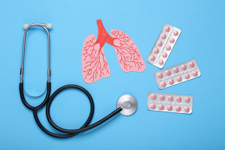 Lung health concept. treatment and diagnosis. Paper cut human lungs and pills with stethoscope on blue backgroundの写真素材