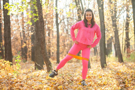 Active fit woman training with fitness band in autumn forest. healthy lifestyle. outdoor workout
