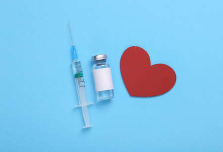 treatment of cardiovascular diseases. Medical bottle with blank label for the brand and syringe with heart on blue background.の写真素材