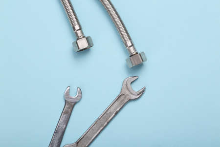 Metal hose and wrench on blue background. Plumber, working concept. Top view, flat layの写真素材