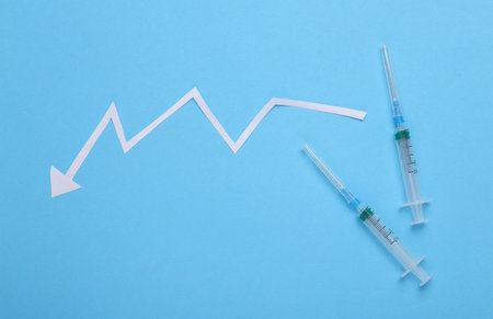 Statistics of vaccination or incidence of covid 19. Syringe with falling arrow on a blue background