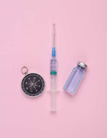 medicine concept. Vaccine bottle with syringe and compass on a pink background. top viewの写真素材