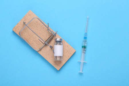 Mousetrap with a bottle of vaccine and a syringe on a blue background