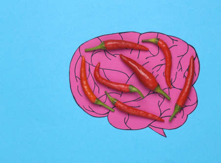 Attack of headache, migraine. Brain with chili pepper on blue background