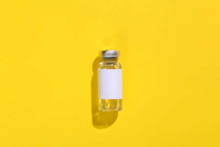 Vaccine bottle with blank label on yellow bright background. top viewの写真素材