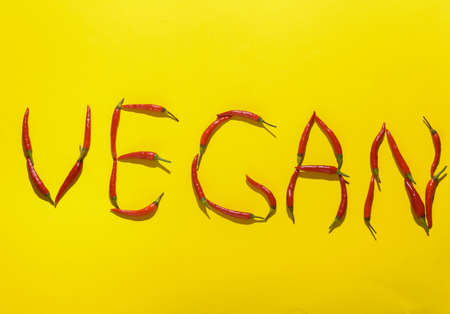 Word vegan made from red chili peppers on yellow backgroundの写真素材