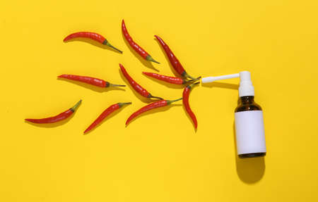 Sore throat. Throat spray with chili pepper on a yellow bright background. creative layoutの写真素材