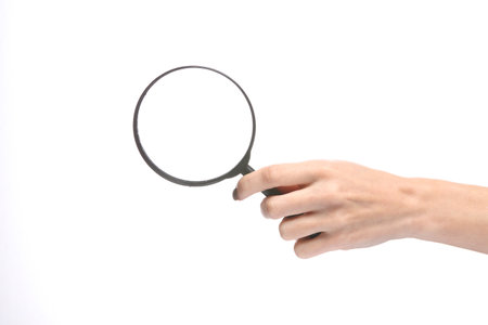 Female hand holding magnifying glass isolated on white backgroundの写真素材