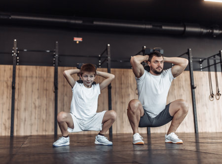 Healthy family concept. Father and his son squats in the gym. Fitness, sports, active lifestyleの写真素材