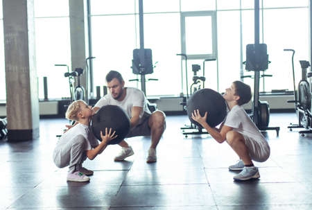 Children's fitness. Two teenager boys are training with a trainer in a modern gym. Training with mid balls, functional training. healthy lifestyleの写真素材