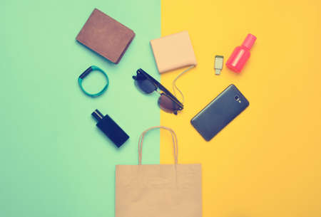 Paper bags and many purchases of gadgets and accessories on a colored background: sunglasses, smartphone, smart bracelet, powel bank, usb flash drive, wallet. consumer concept. top view.の写真素材