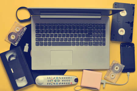 Modern digital gadgets, storage media, devaysy and obsolete analog media devices on a yellow paper background. top view. flat lay.の写真素材