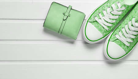 Wallet, sneakers on a white wooden table. Fashionable women's accessories.Top view.の写真素材