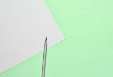 Minimalistic background for copy space, white sheet of paper. Pencil on mint green background.の写真素材