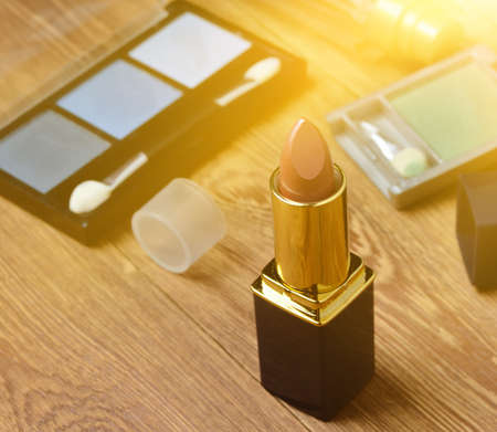 Women's lipstick and make-up cosmetics on a wooden table.の写真素材