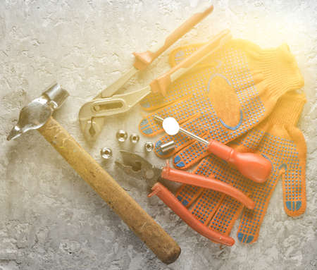 Working tool on a gray concrete surface. Work gloves, hammer, nippers, screwdriver, pliers,...