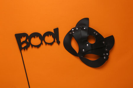 BDSM leather cat mask and the word boo on a stick, orange background. halloween partyの写真素材