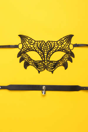 Lace sexy cat mask with leather choker on yellow background. The concept of sexual gamesの写真素材