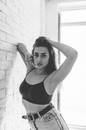 Fashion portrait of a sexy Caucasian woman in top and jeans in bright roomの写真素材