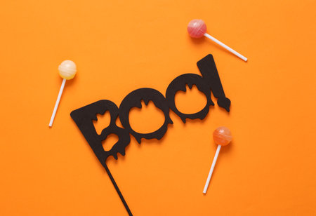 Halloween minimal still life. Word boo with lollipops on orange backgroundの写真素材