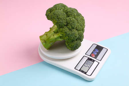 Kitchen scales with broccoli on pink blue background. Slimming, weight loss concept, healthy foodの写真素材
