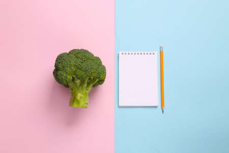 Diet plan. Broccoli with notepad on blue pink pastel backgroundの写真素材