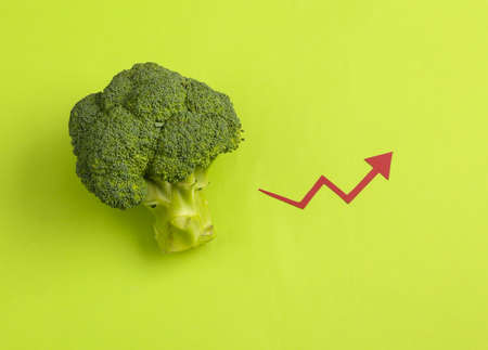 Broccoli with growth arrow on green background. Top viewの写真素材