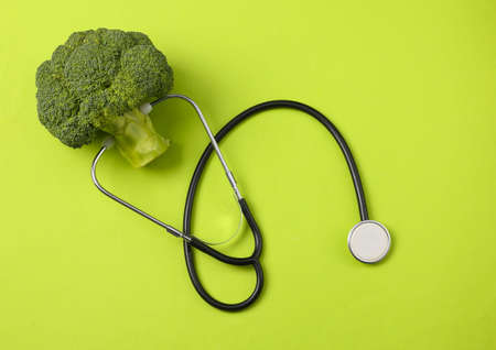 Healthy food concept. Broccoli with stethoscope on green background. Top viewの写真素材