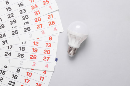 Calendar with Led light bulb on gray background. Top viewの写真素材
