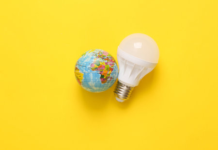 Led light bulb with a globe on a yellow background. Eco concept. Top viewの写真素材