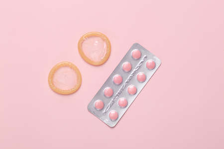 Contraceptives. Condoms and birth control pills on a pink background.の写真素材