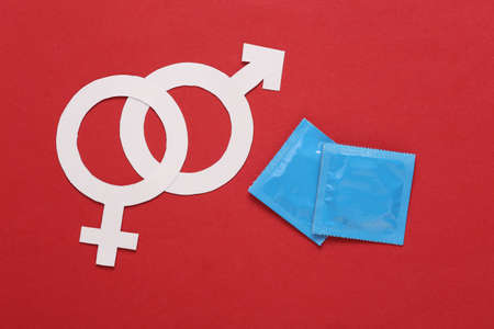 Gender symbols (male and female) with condom packages on a red backgroundの写真素材