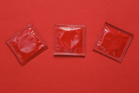 Three red packs of condoms on red background. Top viewの写真素材