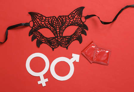 Lace sexy cat mask with packages of condoms and gender symbols on a red background. Role play sexual gamesの写真素材